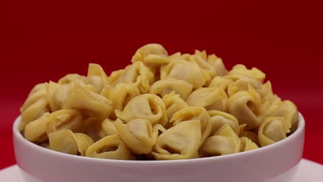 Uncooked-Tortellini-rotating-on-turntable-on-red-background