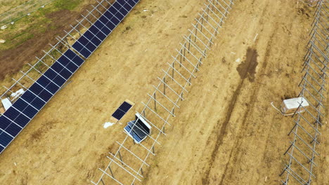 Aerial-top-down-of-photovoltaic-units-during-installation-process-on-grid-on-yellow-field