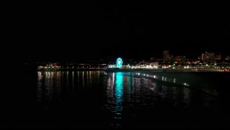 Disparo-Nocturno-De-Un-Dron-Volando-Hacia-Atrás-Revelando-El-Muelle-De-Santa-Mónica