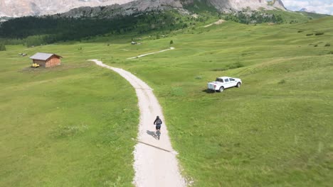 Drones-Aéreos-Rastrean-A-Un-Ciclista-De-Mtb-En-Una-Sinuosa-Carretera-Sin-Pavimentar-En-Pralongia,-Dolomitas-Italianas