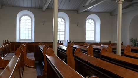 Tracking-view-along-rows-of-vintage-wooden-pews-in-old-Lutheran-Church