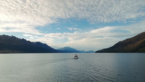 Panoramic-orbit-around-tourboat-in-middle-of-Lake-Wakatipu-on-beautiful-cloudy-day