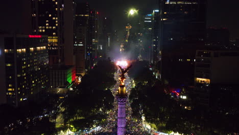 Fireworks-and-the-Angel-of-Independence,-night-in-Mexico-city---Elevated,-drone-shot