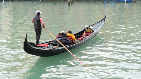 Toma-De-Seguimiento-De-Una-Pareja-De-Ancianos-Dando-Un-Paseo-En-Góndola-En-Venecia,-Italia