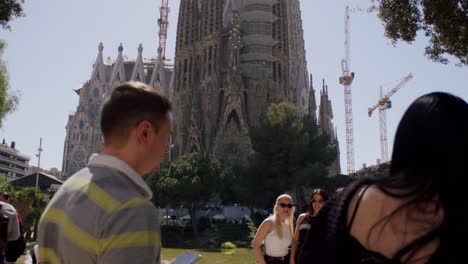 Tourists-enjoying-the-view-of-the-Sagrada-Familia-in-Barcelona-under-the-clear-blue-sky,-daytime