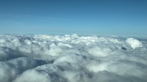 Cloudscape-pilot-POV-flying-over-stormy-clouds-in-a-sunny-day-with-a-deep-blue-sky