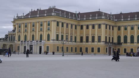 Schönbrunn-Palace-in-Vienna-on-a-cold-and-cloudy-afternoon,-tourists-touring-the-grounds