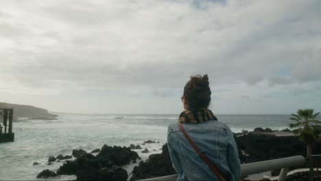 Woman-tourist-enjoying-view-on-waves-crashing-on-the-rocky-coast-of-Garachico-town-on-Tenerife,-Canary-Islands