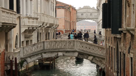 People-crossing-bridges-over-Venice-Canal,-Bridge-of-Sighs-in-background