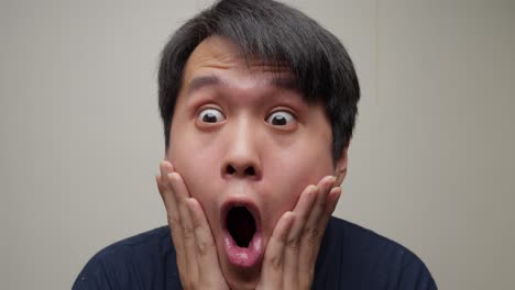 Close-up-shot-reveals-an-Asian-man's-face,-his-eyes-wide-with-astonishment-as-he-gazes-intently-forward