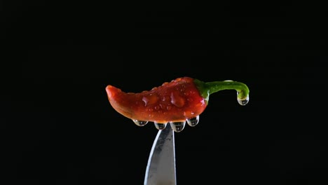 Water-Trickling-Down-From-a-Chili-Pierced-by-a-Knife-Against-Black-Backdrop---Close-Up