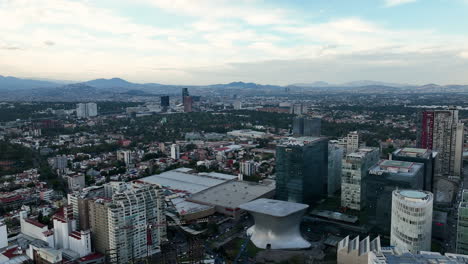 Aerial-view-backwards-over-unique-buildings-in-Polanco,-evening-in-Mexico-city