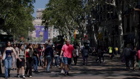 Two-young-women-walking-on-La-Rambla,-Barcelona,-bustling-street-vibe,-daytime