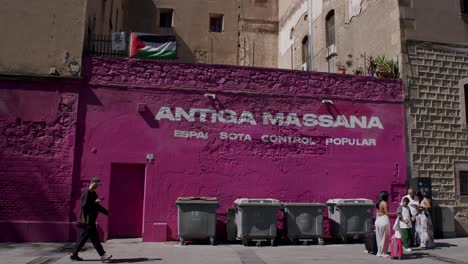 Vibrant-pink-wall-with-"Antiga-Massana"-graffiti-in-Barcelona,-people-passing-by