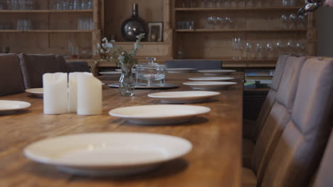 A-woman-placing-cutlery-at-a-large-wooden-dining-table