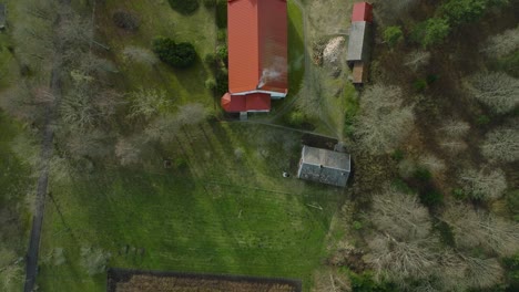Aerial-view-of-a-white-church-with-red-roof-on-a-sunny-spring-day,-wide-birdseye-drone-shot-moving-forward