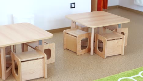 Pair-of-small-wooden-tables,-benches-for-students-in-kindergarten-classroom