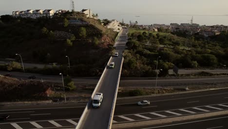 Aerial-reverse-view-of-campervan-convoy-crossing-freeway-bridge-near-Malaga,-Spain