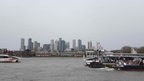Capturing-the-scenic-view-of-Greenwich-Pier-against-the-backdrop-of-the-iconic-Canary-Wharf-skyline,-embodying-the-concept-of-juxtaposition-between-historic-charm-and-modern-grandeur