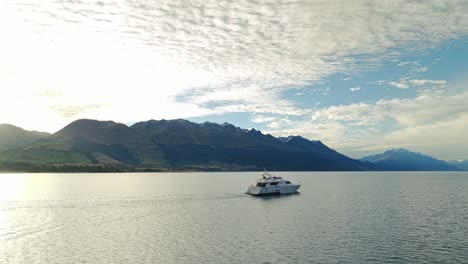 órbita-Aérea-A-Través-De-Un-Lago-De-Textura-Tranquila-Con-Un-Paisaje-Nublado-épico-Mientras-El-Sol-Se-Esconde-Debajo-De-Las-Montañas