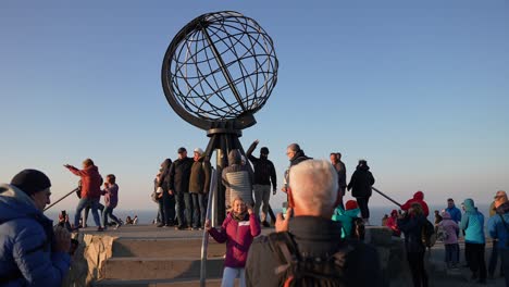 Tourists-Taking-Photos-Under-Globe-Monument-on-North-Cape-of-Norway-at-Sunset-60fps