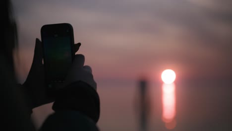 Close-up-of-a-sunset-captured-on-a-phone-at-Burano-Island,-Venice