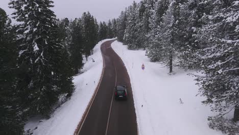 Toma-Aérea-De-Seguimiento-De-Un-Automóvil-Peugeot-En-La-Carretera-De-Lavaze-Pass-Durante-El-Invierno-Nevado-En-Las-Montañas-Italianas.