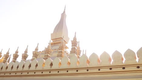 Llamarada-Del-Sol-A-Través-De-Las-Agujas-Doradas-Del-Templo-De-La-Estupa-Dorada-De-Pha-That-Luang-En-Vientiane,-Laos