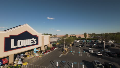 FPV-drone-flight-over-Lowe’s-retail-company-in-american-town-with-many-parking-cars-at-sunset