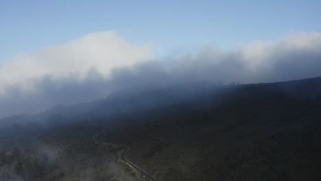 Stratus-clouds-flow-gently-down-slopes-of-Haleakala-above-winding-road-in-Maui
