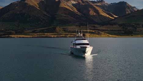 Frontal-aerial-orbit-parallax-around-yacht-tour-at-base-of-mountains-over-Lake-Wakatipu