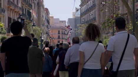 Stilt-walker-performing-at-a-busy-street-festival-in-Barcelona,-surrounded-by-a-crowd-in-daylight