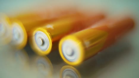 Macro-video-of-a-pile-of-rolling-batteries-on-a-desk-with-reflection,-golden-battery,-slow-motion-120-fps,-Full-HD