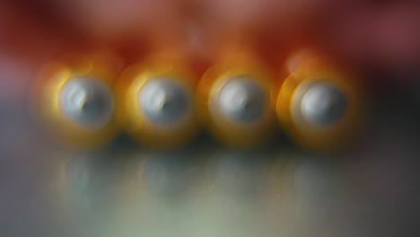 Macro-video-of-a-pile-of-rolling-batteries-on-a-desk-with-reflection,-golden-battery,-slow-motion-120-fps,-Full-HD,-reveal-smooth-movement