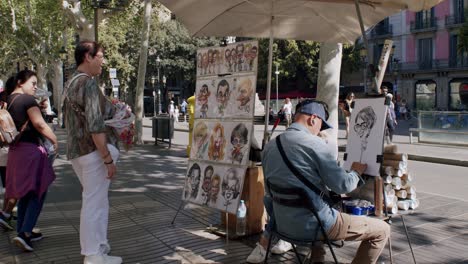 Artista-Callejero-Dibujando-Retratos-Para-Turistas-En-Una-Concurrida-Plaza-De-Barcelona,-Día-Soleado