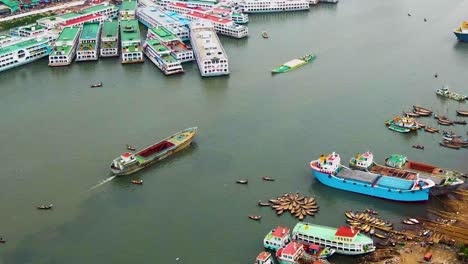 Aerial-shot-of-cargo-boats-sailing-and-ferry-ship-moored-at-a-river-in-Bangladesh
