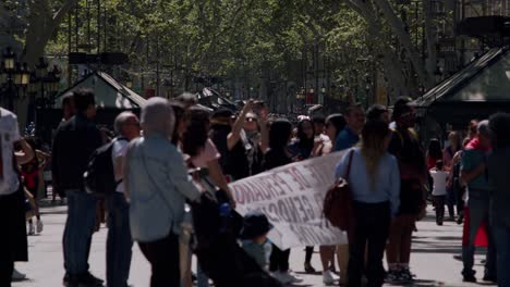 Crowded-Barcelona-street-scene-with-people-and-protest-sign-in-daylight