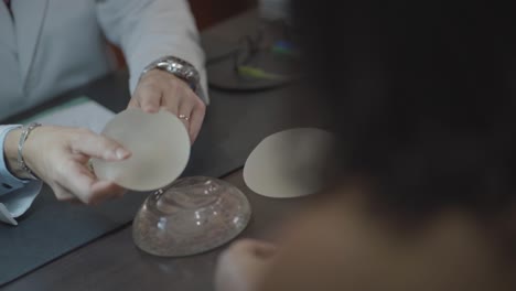 Slow-motion-doctor-and-patient-touching-silicone-breast-prosthesis-close-up,-poking-with-finger