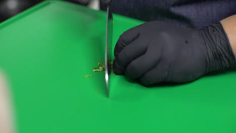 Chef-hands-cutting-parsley-on-a-green-cutting-board,-close-up