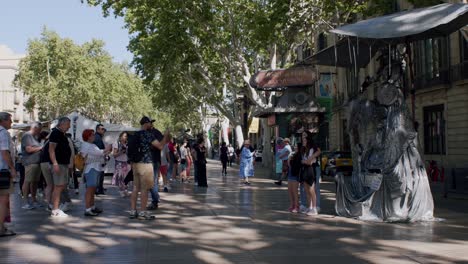Sunny-day-at-a-bustling-La-Rambla-street-with-tourists-and-a-living-statue-in-Barcelona