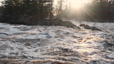 Sunbeams-casting-a-warm-glow-on-a-roaring-river-surging-with-spring-snowmelt