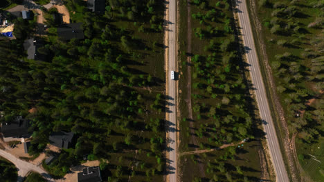 Top-down-drone-shot-following-a-camper-driving-in-the-Saariselka-town,-Finland