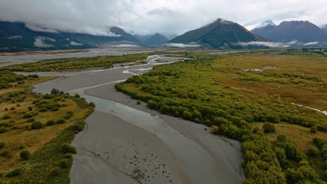 Aerial-pullback-above-sediment-deposits-on-riverbank-delta-in-Glenorchy-on-overcast-day