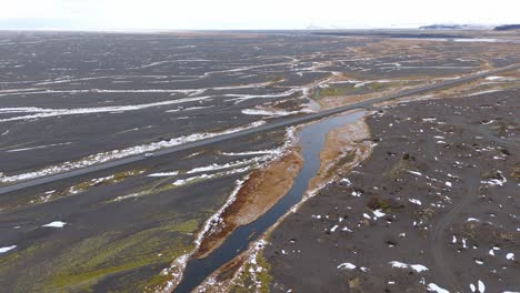 Volcanic-soil-landscape,-aerial-drone,-white-car-drive-through-Icelandic-nature