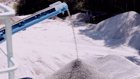 Conveyor-belt-distributing-crushed-stone-creating-mounds-in-a-mining-quarry