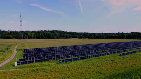 Rotierende-Luftaufnahme-Eines-Solarparks-Zwischen-üppigen-Goldenen-Und-Grünen-Feldern