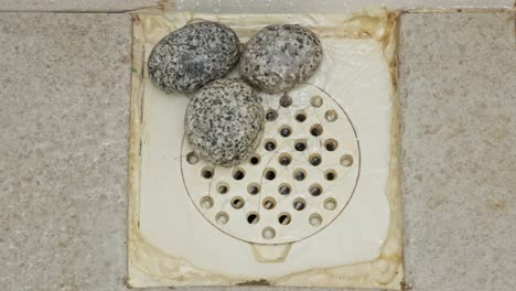 Three-Pieces-Of-Natural-Pumice-Stones-In-A-Bathroom-Drainage