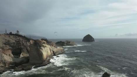 Costa-De-Cabo-Kiwanda-Con-Olas-Tormentosas-Y-Parapente-Sobre-La-Costa,-Costa-De-Oregon,-EE.UU.