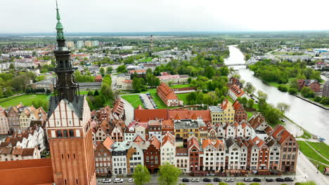 Blick-Aus-Der-Vogelperspektive-Auf-Die-Altstadt-Von-Elbląg-Mit-Historischer-Architektur,-Dem-Kirchturm-Im-Vordergrund-Und-Einem-Fluss-In-Der-Ferne