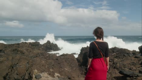 Woman-admires-the-huge-waves-crashing-on-the-rocky-shore